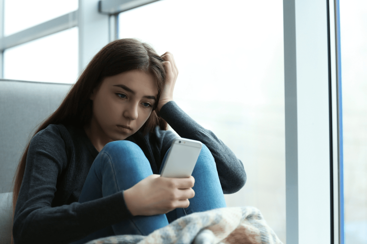 Distressed girl looking at phone