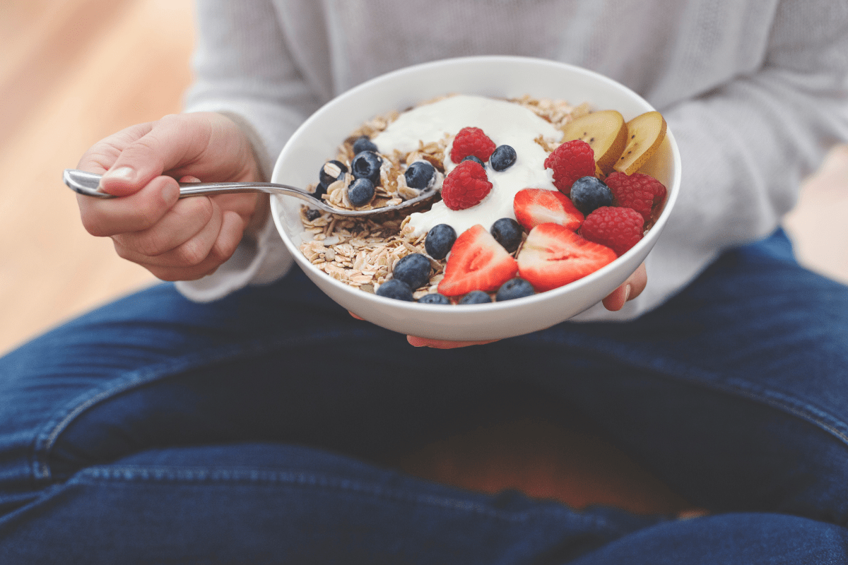 Person scooping from bowl of oatmeal with fruit