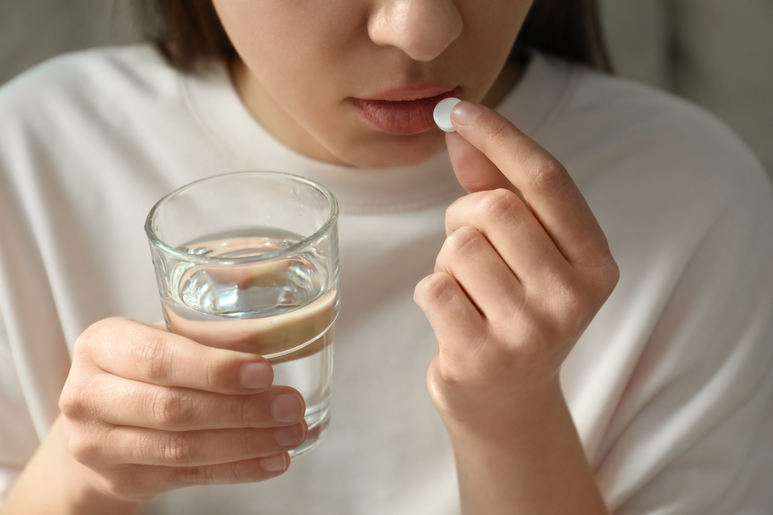 Girl holding a pill and glass of water